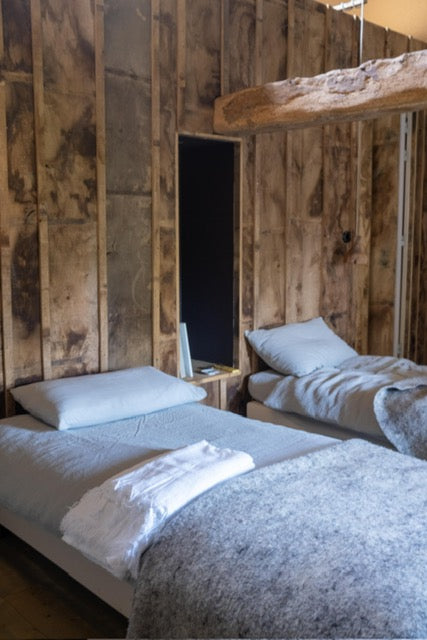 Les lits de l'une des chambres doubles de l'Arbre qui marche devant leur magnifique mur en bois. Photo Nathalie Baetens