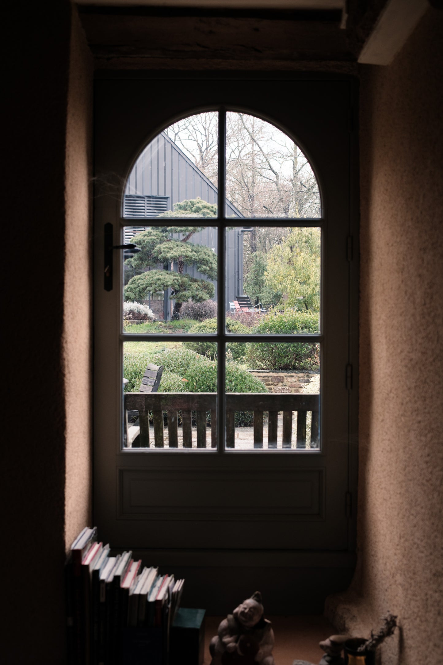 Vue sur la terrasse paysagée et le hangar de L'Arbre qui marche depuis la fenêtre du salon. Photo : Antoine Sorel.