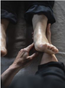 des main pratiquent la réflexologie sur un pied à l'Arbre qui marche, l'image est centré sur ce geste