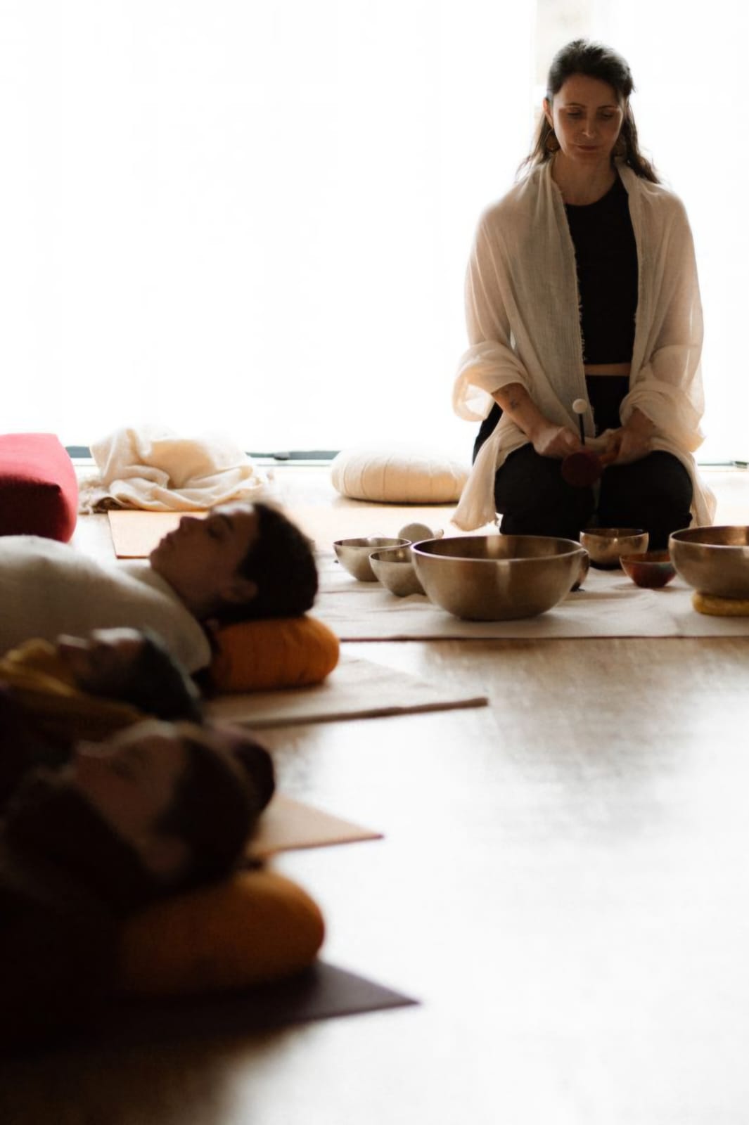 Fanny Guiraud, professeure de yoga et sonothérapeute, pendant une séance de yoga nidra thérapeutique, entourée de bols